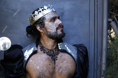 Kral tacı ve ayna topuyla şık bir karnaval kostümü giymiş yakışıklı genç adamın yakın plan portresi.