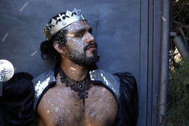 Kral tacı ve ayna topuyla şık bir karnaval kostümü giymiş yakışıklı genç adamın yakın plan portresi.