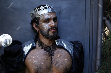 Kral tacı ve ayna topuyla şık bir karnaval kostümü giymiş yakışıklı genç adamın yakın plan portresi.