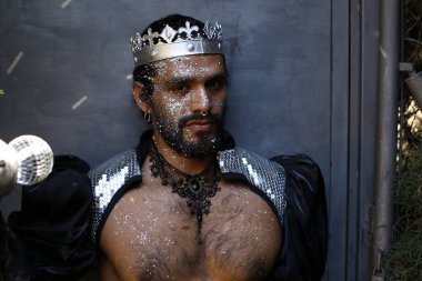 Kral tacı ve ayna topuyla şık bir karnaval kostümü giymiş yakışıklı genç adamın yakın plan portresi.