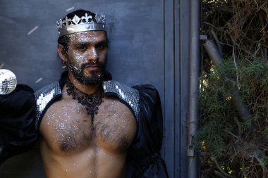 Kral tacı ve ayna topuyla şık bir karnaval kostümü giymiş yakışıklı genç adamın yakın plan portresi.