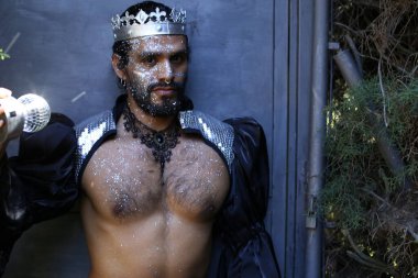 Kral tacı ve ayna topuyla şık bir karnaval kostümü giymiş yakışıklı genç adamın yakın plan portresi.