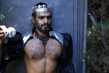 Kral tacı ve ayna topuyla şık bir karnaval kostümü giymiş yakışıklı genç adamın yakın plan portresi.