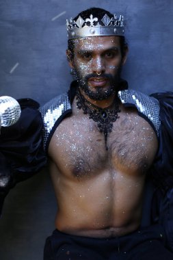 Kral tacı ve ayna topuyla şık bir karnaval kostümü giymiş yakışıklı genç adamın yakın plan portresi.