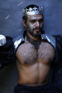 Kral tacı ve ayna topuyla şık bir karnaval kostümü giymiş yakışıklı genç adamın yakın plan portresi.