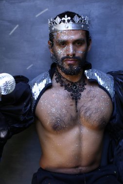 Kral tacı ve ayna topuyla şık bir karnaval kostümü giymiş yakışıklı genç adamın yakın plan portresi.