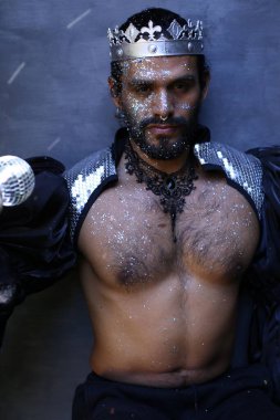 Kral tacı ve ayna topuyla şık bir karnaval kostümü giymiş yakışıklı genç adamın yakın plan portresi.