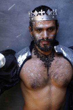 Kral tacı ve ayna topuyla şık bir karnaval kostümü giymiş yakışıklı genç adamın yakın plan portresi.