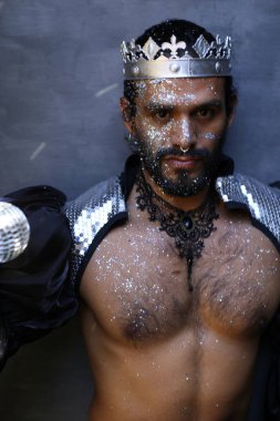 Kral tacı ve ayna topuyla şık bir karnaval kostümü giymiş yakışıklı genç adamın yakın plan portresi.