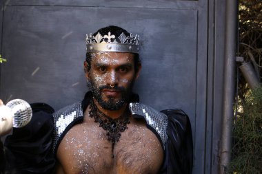 Kral tacı ve ayna topuyla şık bir karnaval kostümü giymiş yakışıklı genç adamın yakın plan portresi.