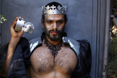 Kral tacı ve ayna topuyla şık bir karnaval kostümü giymiş yakışıklı genç adamın yakın plan portresi.