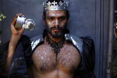 Kral tacı ve ayna topuyla şık bir karnaval kostümü giymiş yakışıklı genç adamın yakın plan portresi.