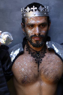 Kral tacı ve ayna topuyla şık bir karnaval kostümü giymiş yakışıklı genç adamın yakın plan portresi.