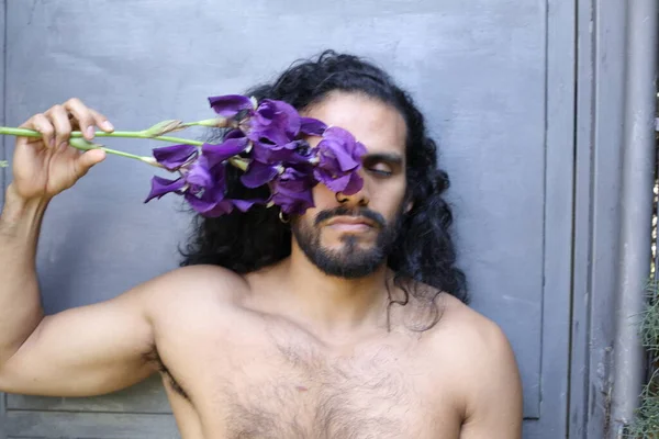年轻英俊无袖男子的特写 手持紫色兰花 — 图库照片