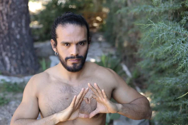 Yakından bakınca, elleri ile kalp şeklinde hareket eden yakışıklı, üstsüz genç bir adamın portresi.