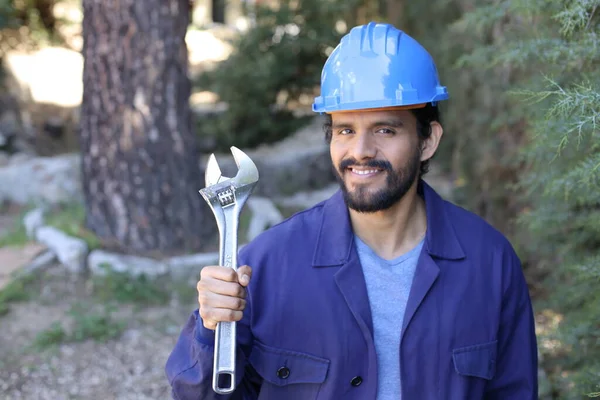 Açık havada ingiliz anahtarı takan yakışıklı bir tesisatçı portresi.