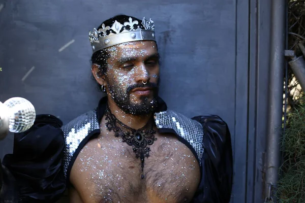 Kral tacı ve ayna topuyla şık bir karnaval kostümü giymiş yakışıklı genç adamın yakın plan portresi.