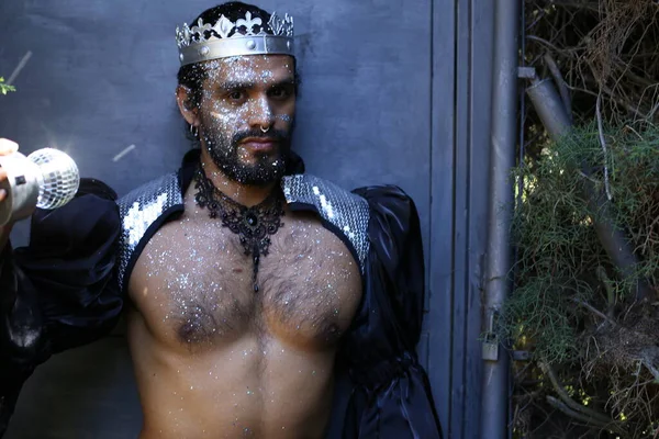 Kral tacı ve ayna topuyla şık bir karnaval kostümü giymiş yakışıklı genç adamın yakın plan portresi.