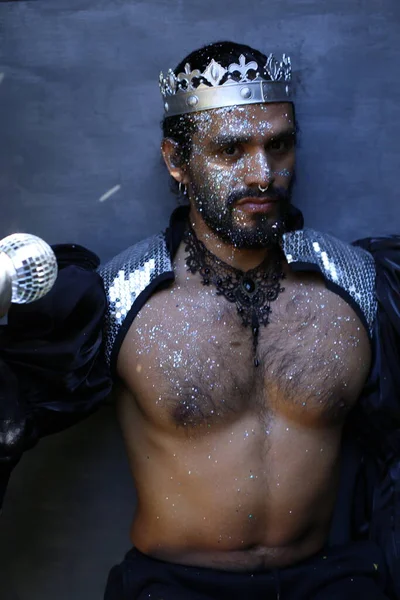 Kral tacı ve ayna topuyla şık bir karnaval kostümü giymiş yakışıklı genç adamın yakın plan portresi.