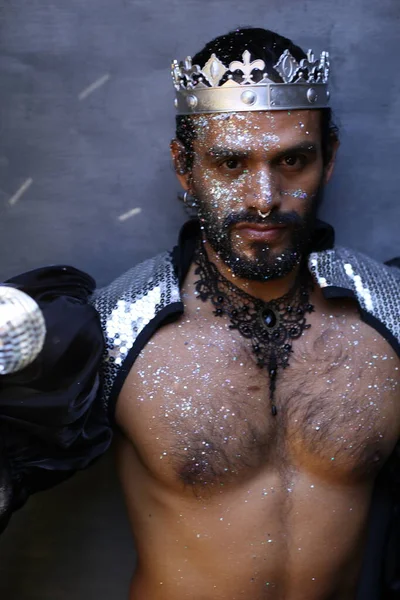 Kral tacı ve ayna topuyla şık bir karnaval kostümü giymiş yakışıklı genç adamın yakın plan portresi.