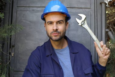 Üniformalı, miğferi ve anahtarı olan yakışıklı genç işçinin yakın plan portresi.