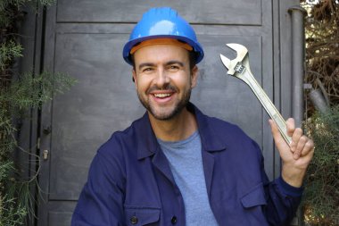 Üniformalı, miğferi ve anahtarı olan yakışıklı genç işçinin yakın plan portresi.