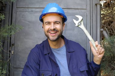 Üniformalı, miğferi ve anahtarı olan yakışıklı genç işçinin yakın plan portresi.