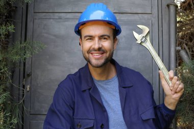 Üniformalı, miğferi ve anahtarı olan yakışıklı genç işçinin yakın plan portresi.