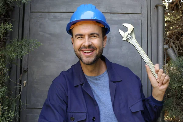 Üniformalı, miğferi ve anahtarı olan yakışıklı genç işçinin yakın plan portresi.