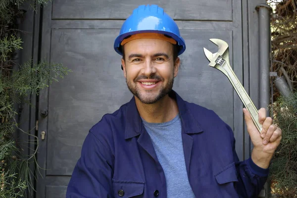 Üniformalı, miğferi ve anahtarı olan yakışıklı genç işçinin yakın plan portresi.