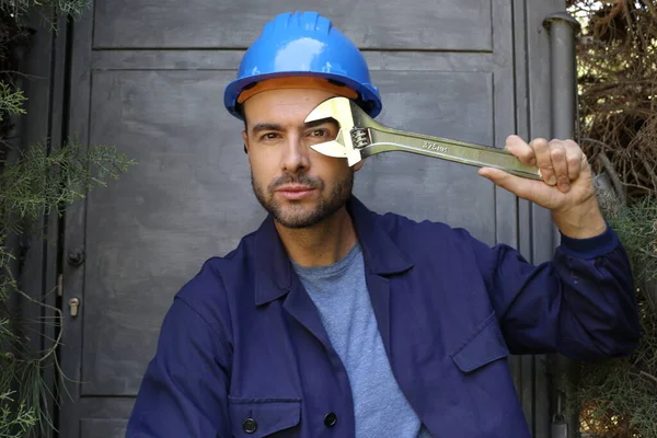 Üniformalı, miğferi ve anahtarı olan yakışıklı genç işçinin yakın plan portresi.