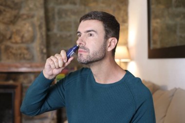 Evinde burun kesicisi olan yakışıklı bir gencin yakın plan portresi.