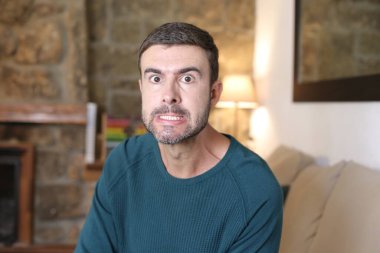 Evinde somurtan yakışıklı genç adamın yakın plan portresi.