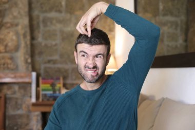 Evinde somurtan yakışıklı genç adamın yakın plan portresi.