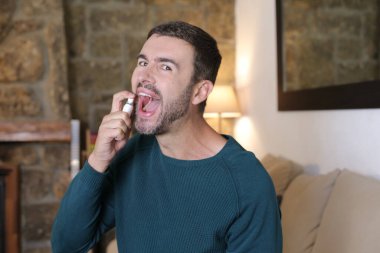 Evinde ağzına nane püskürten yakışıklı bir gencin yakın plan portresi.