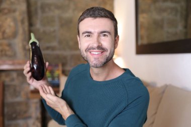 Evde olgun patlıcan tutan yakışıklı bir gencin yakın plan portresi.