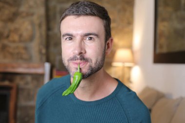 Evde yeşil biberli yakışıklı bir gencin yakın plan portresi.