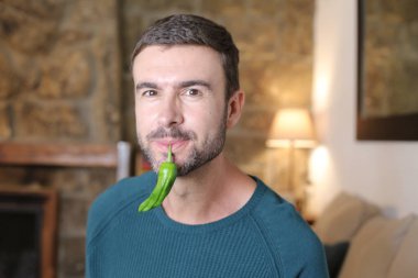 Evde yeşil biberli yakışıklı bir gencin yakın plan portresi.