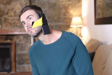 Evinde yüzüne akıllı telefon dikilmiş yakışıklı bir gencin yakın plan portresi.