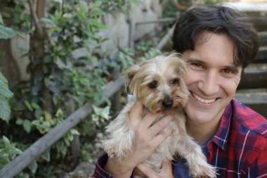 Küçük şirin bir köpek yavrusu tutan yakışıklı genç adamın portresi.