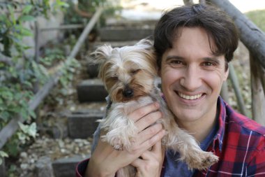 Küçük şirin bir köpek yavrusu tutan yakışıklı genç adamın portresi.