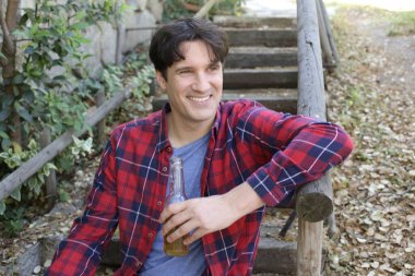 Elinde bira şişesi olan yakışıklı bir gencin portresi.