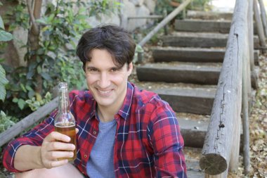 Elinde bira şişesi olan yakışıklı bir gencin portresi.