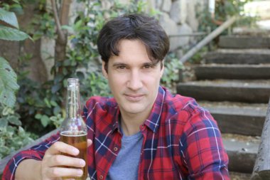 Elinde bira şişesi olan yakışıklı bir gencin portresi.