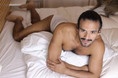 Yatakta genç ve yakışıklı bir adamın yakın plan portresi.