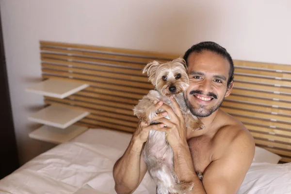在床上抱着可爱的小狗的年轻帅小伙裸男的特写 — 图库照片