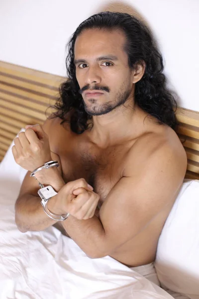 手錠をかけられたベッドでハンサムな若い白人男性のクローズアップポートレート — ストック写真