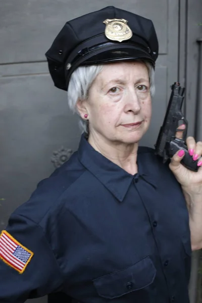 グレーウォールを背景に警察制服を着た熟女のクローズアップ肖像画 — ストック写真