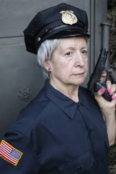 グレーウォールを背景に警察制服を着た熟女のクローズアップ肖像画 — ストック写真