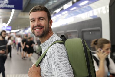 Tren istasyonunda sırt çantalı yakışıklı bir gencin yakın plan portresi.